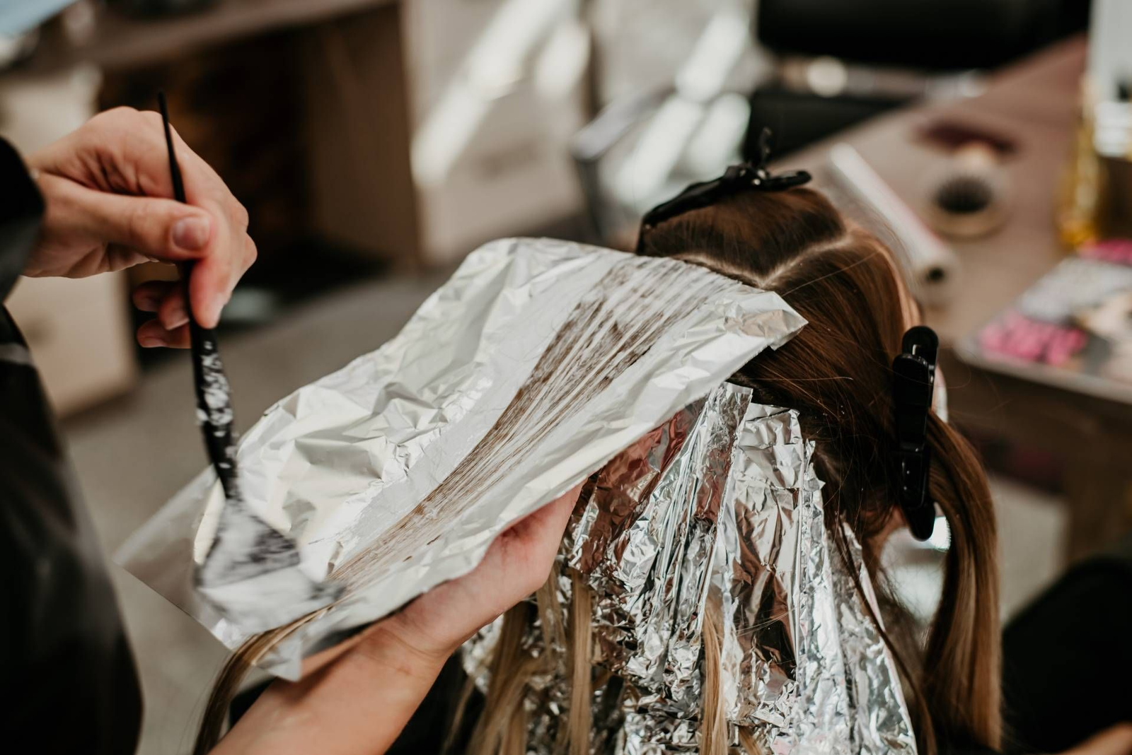 Colorista profissional aplicando técnica de mechas com segurança em salão de beleza